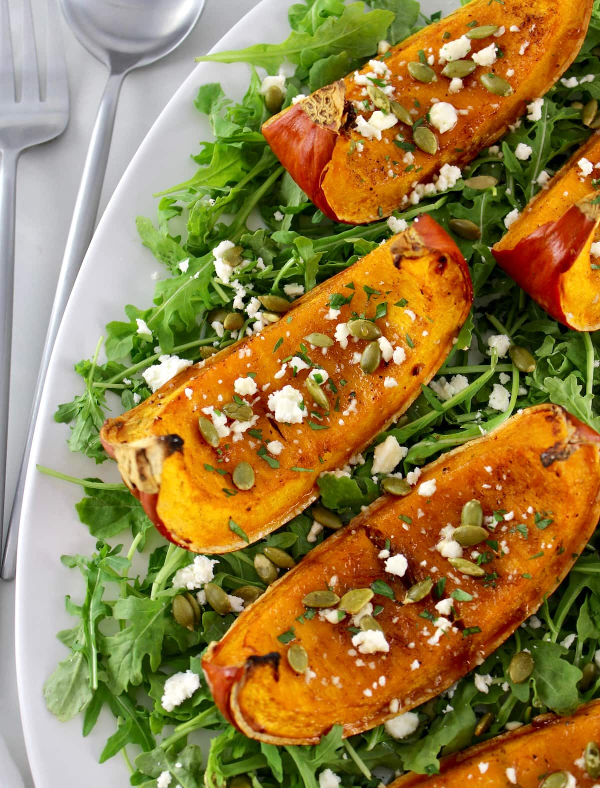 closeup of Roasted Pumpkin on arugula on white platter
