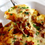 spoon lifting a Stuffed Shells with Meat Sauce out of casserole with cheese pulling