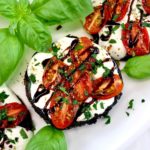 closeup of Caprese Stuffed Portobellos on white plate with balsamic drizzle and fresh basil