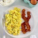 Ricotta Scrambled Eggs on white plate with 2 pieces of back and fork on side