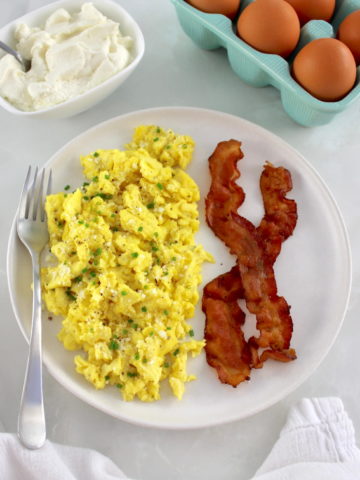 Ricotta Scrambled Eggs on white plate with 2 pieces of back and fork on side