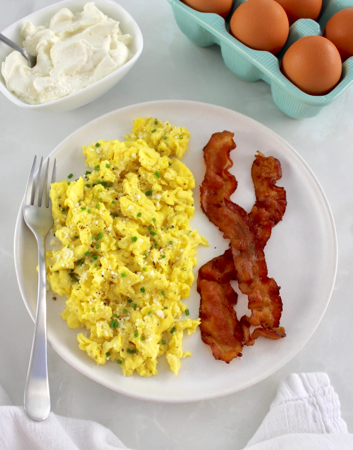 Ricotta Scrambled Eggs on white plate with 2 pieces of back and fork on side
