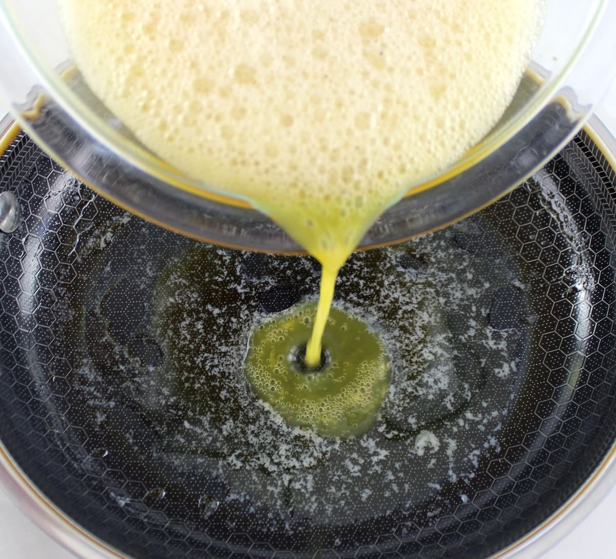 beaten eggs being poured into skillet with butter