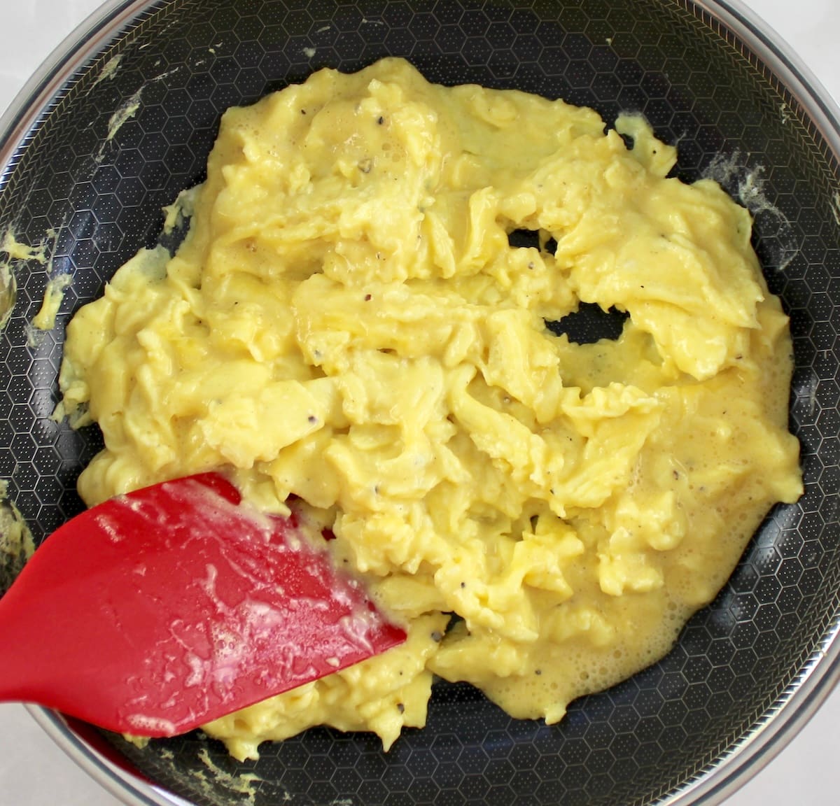 Ricotta Scrambled Eggs in skillet with red spatula