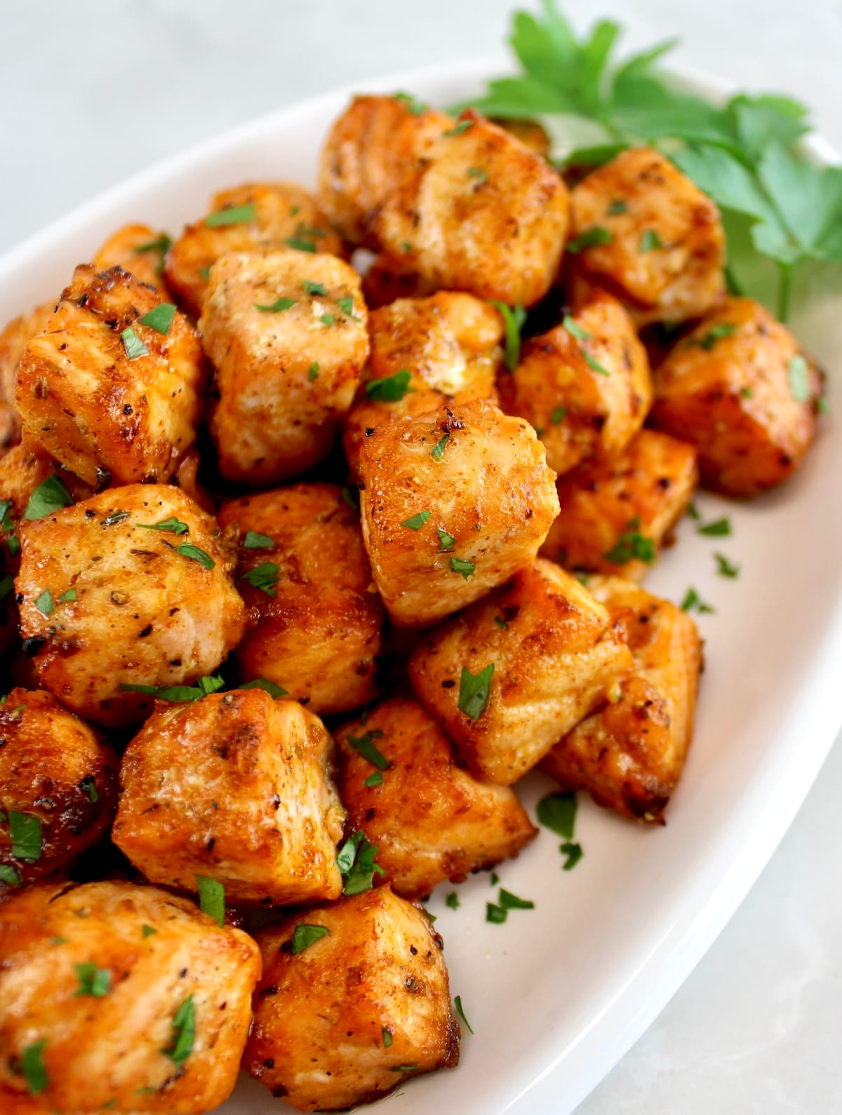 closeup of Cajun Salmon Bites on white plate with parsley