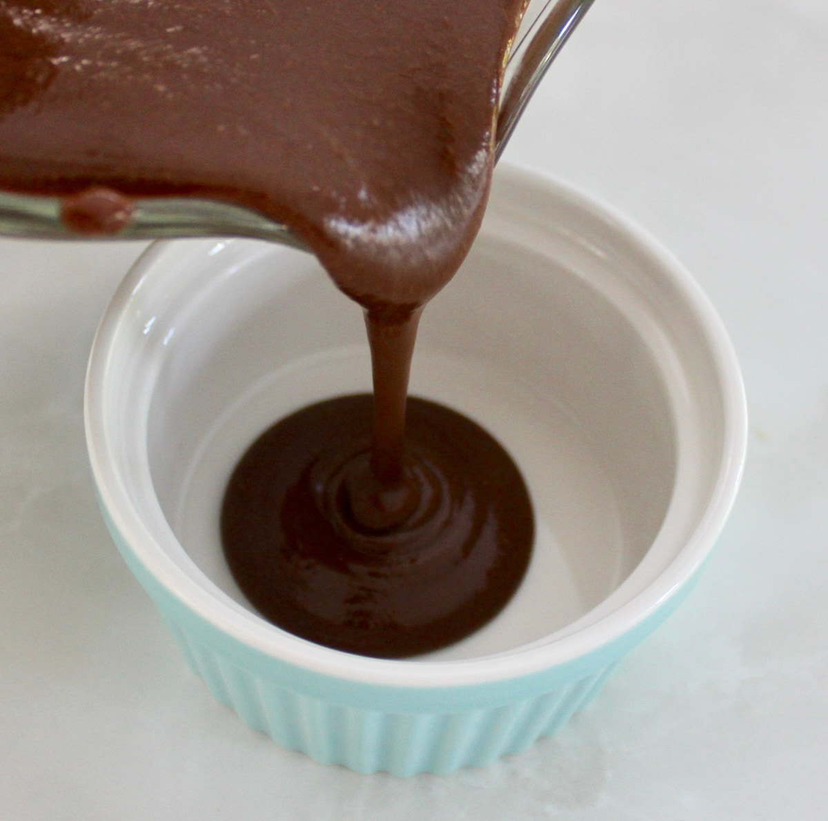 pouring Chocolate Pots de Crème custards into blue ramekin
