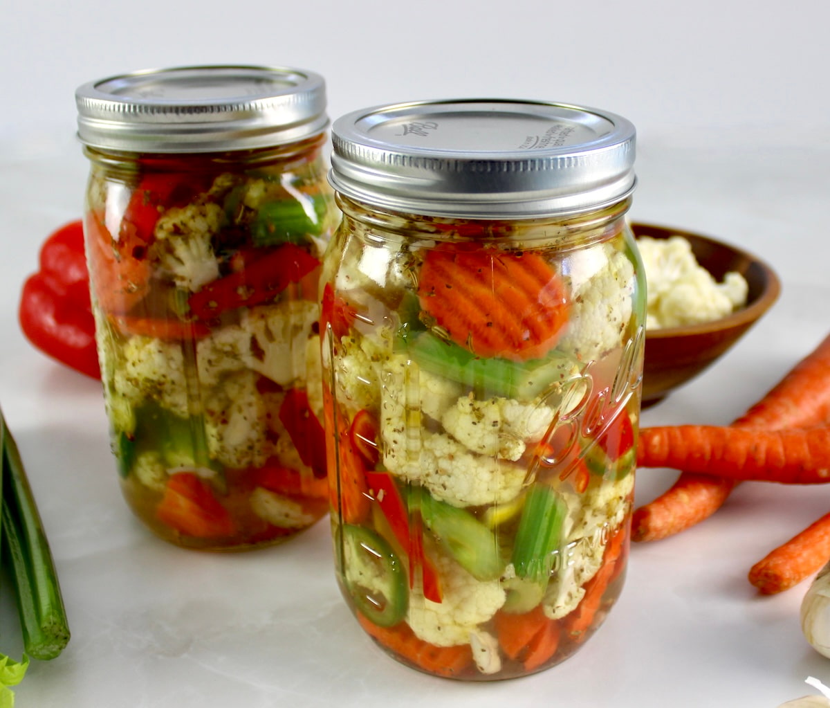 Easy Homemade Giardiniera in 2 glass jars with veggies in back