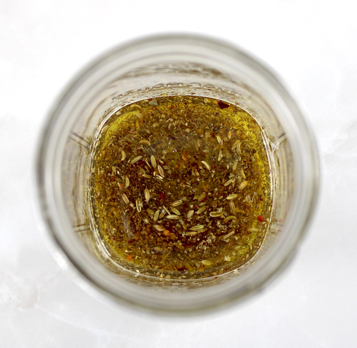 herbs, olive oil and seeds in open glass jar