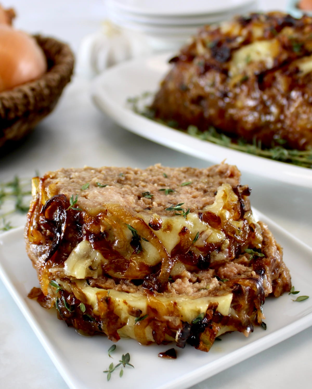 2 slices of French Onion Meatloaf on white plate with more in back
