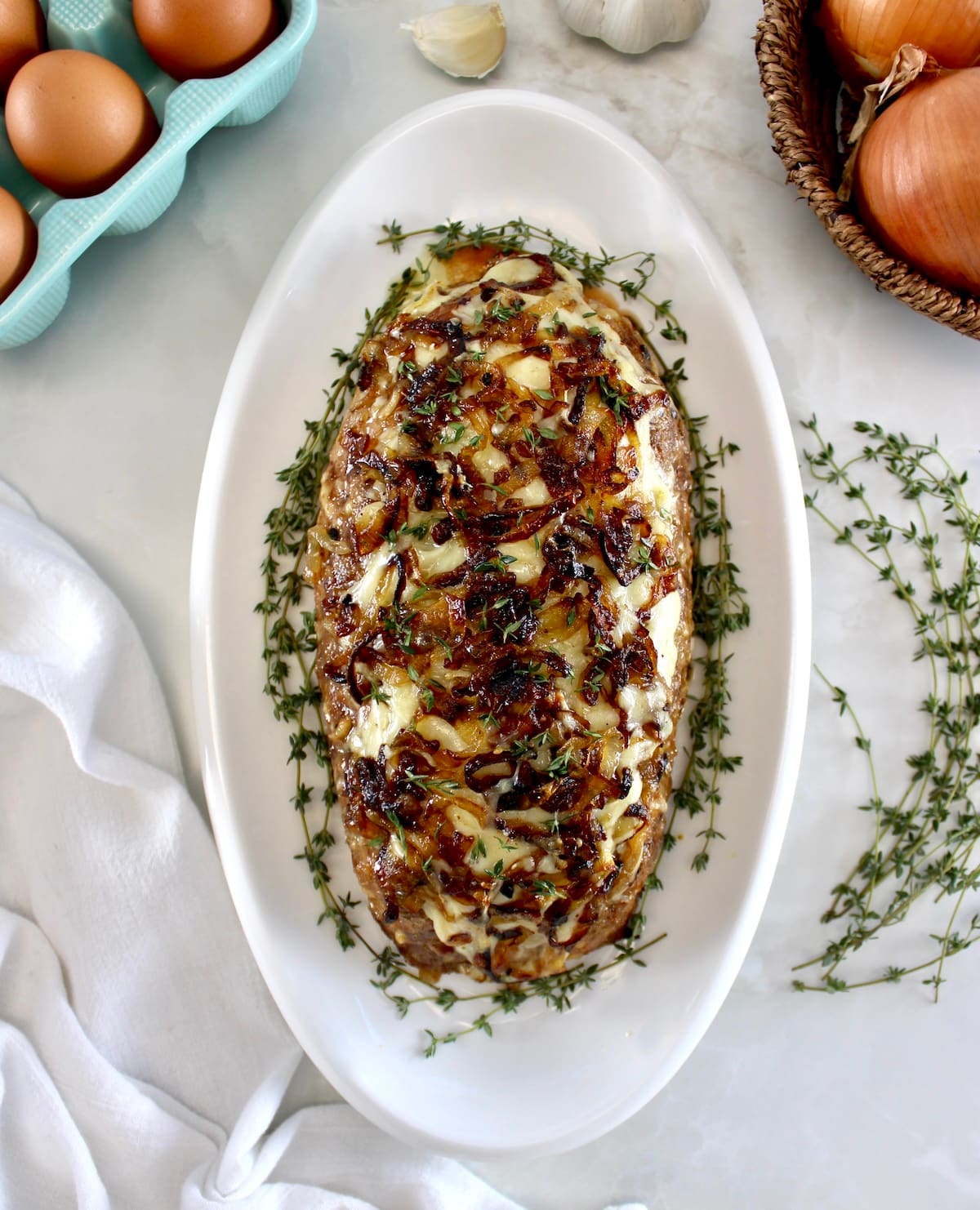 overhead view of French Onion Meatloaf on white oval platter with fresh thyme