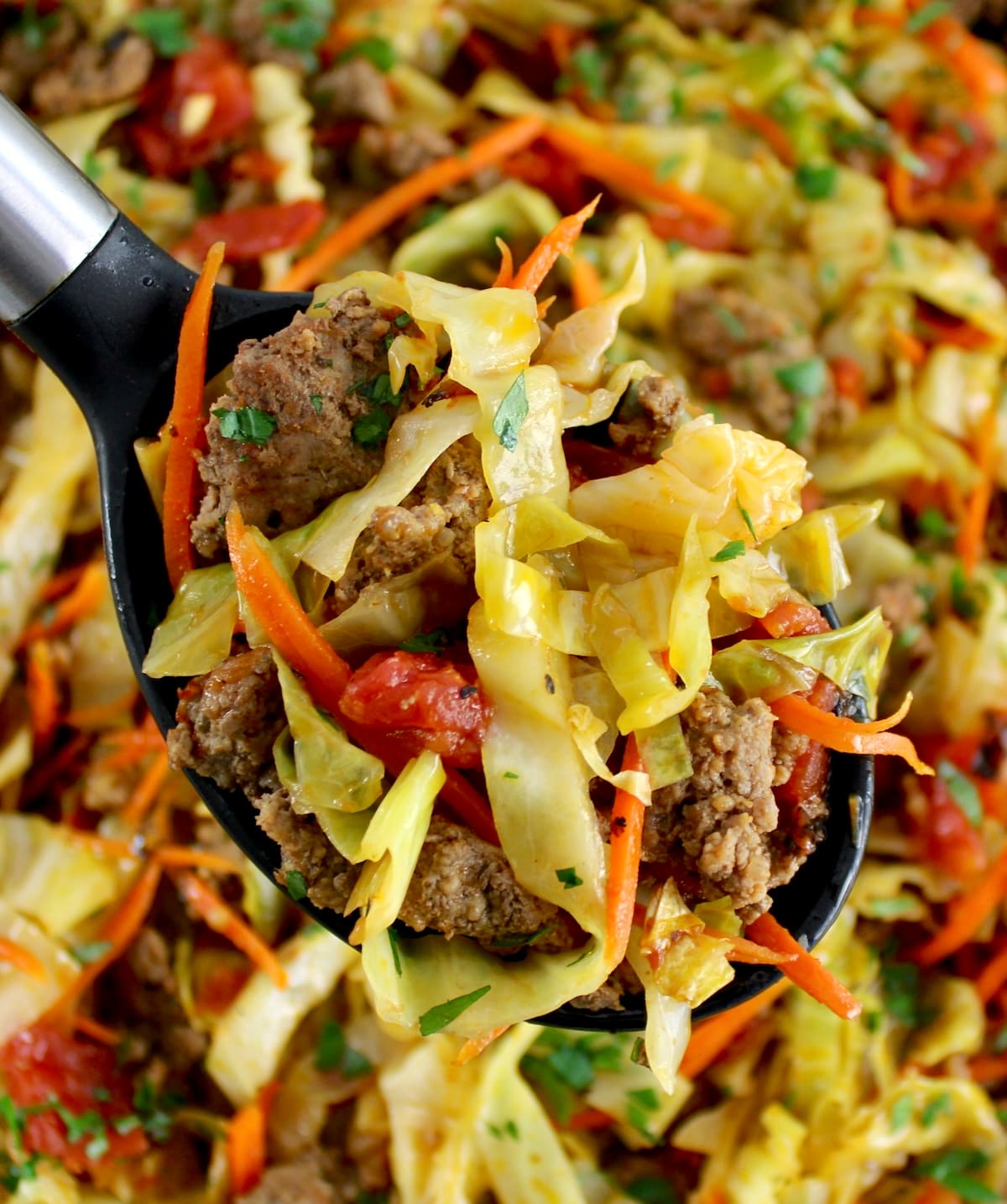 Ground Beef and Cabbage Skillet in ladle held up over skillet