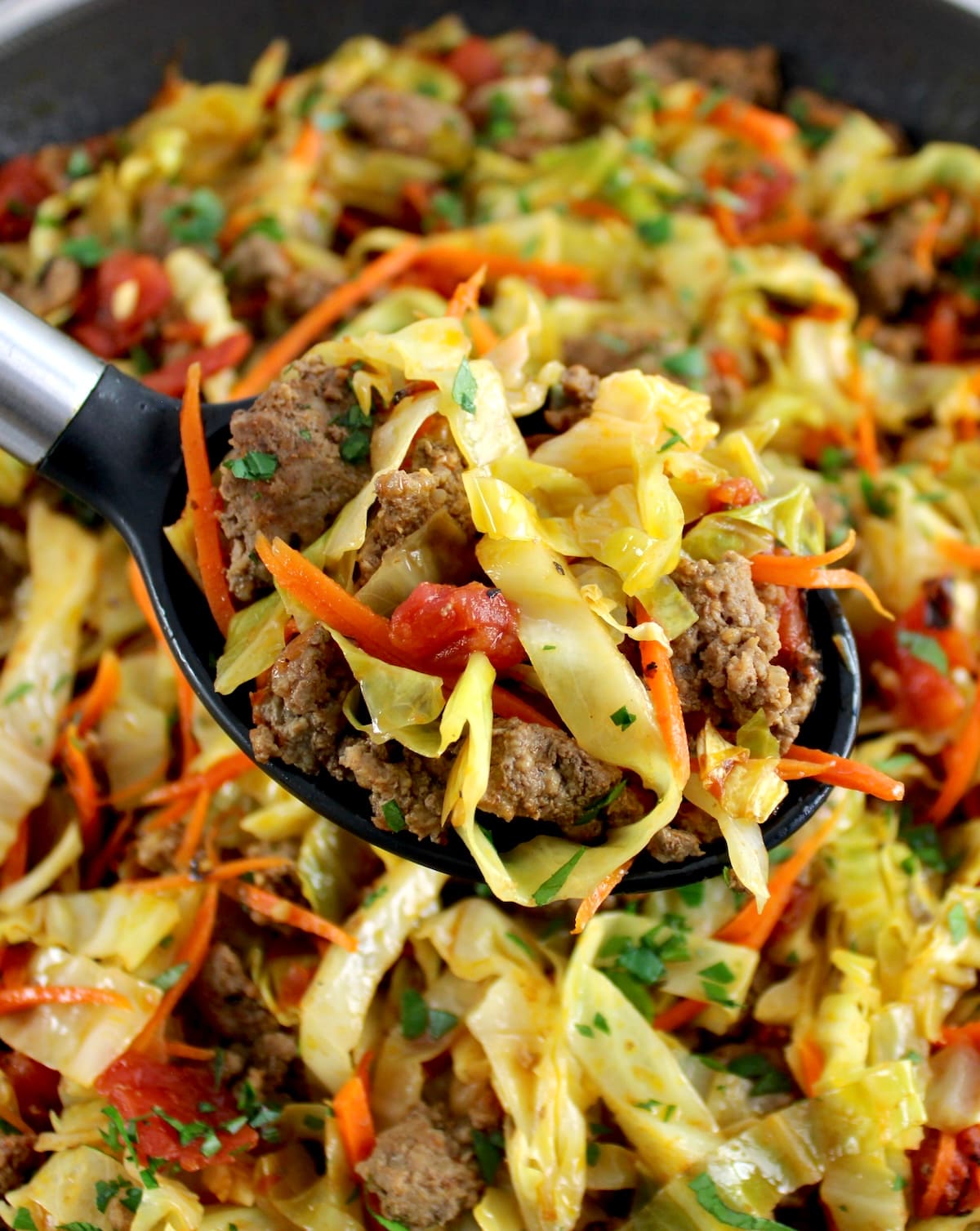Ground Beef and Cabbage Skillet in ladle held up over skillet