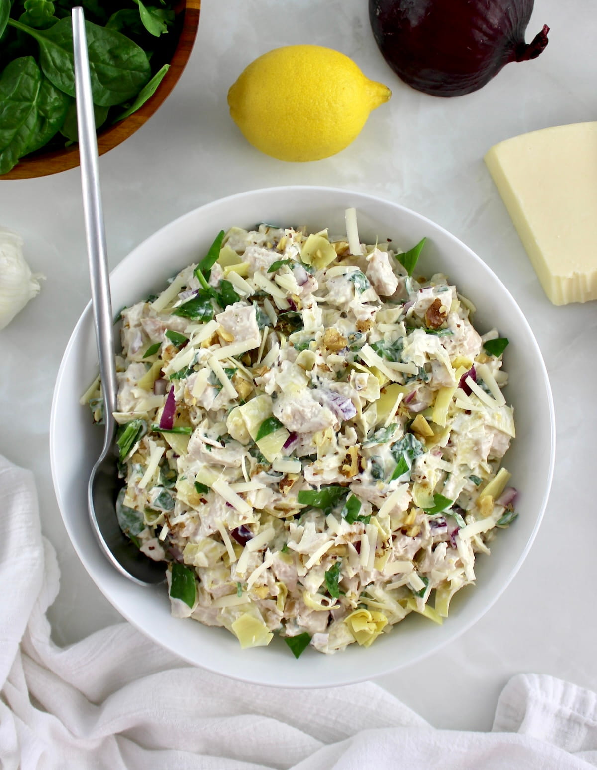 Spinach Artichoke Chicken Salad in white bowl with spoon on side