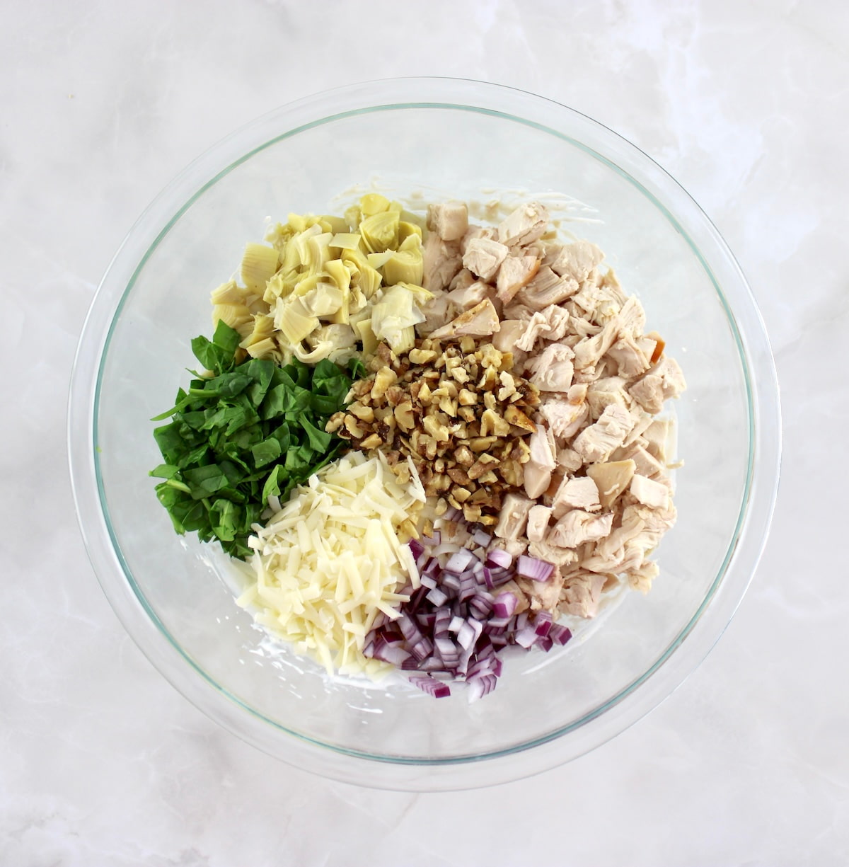 Spinach Artichoke Chicken Salad ingredients in glass bowl in sections unmixed