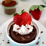 Chocolate Mug Cake with whip cream and sliced strawberry on top