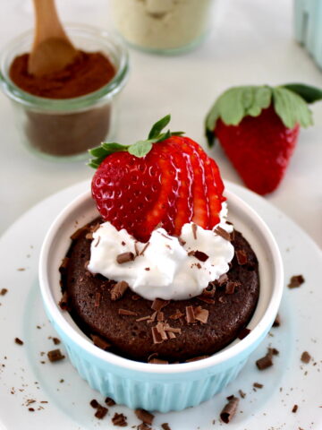 Chocolate Mug Cake with whip cream and sliced strawberry on top