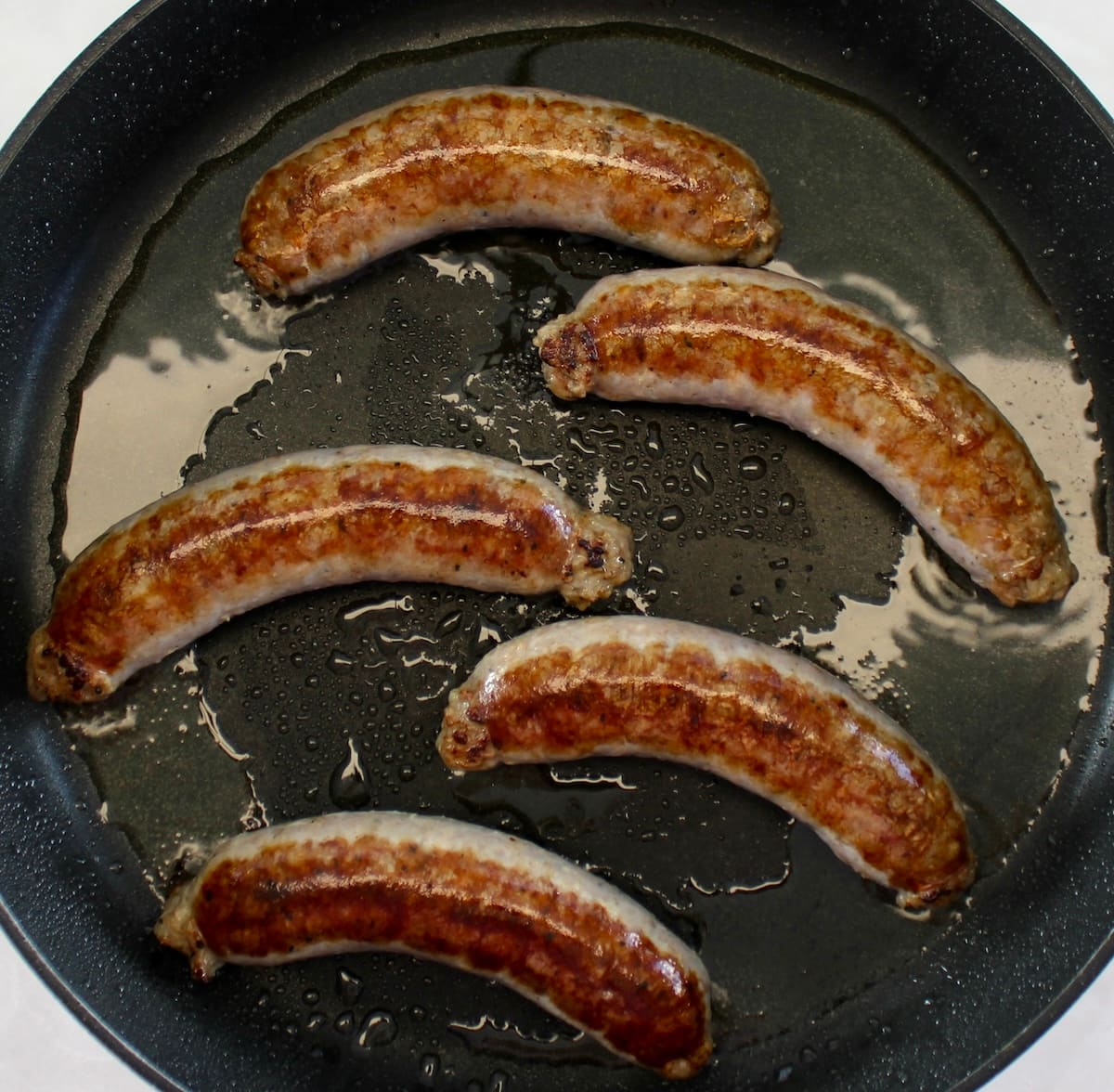 5 Italian sausage links cooking in skillet