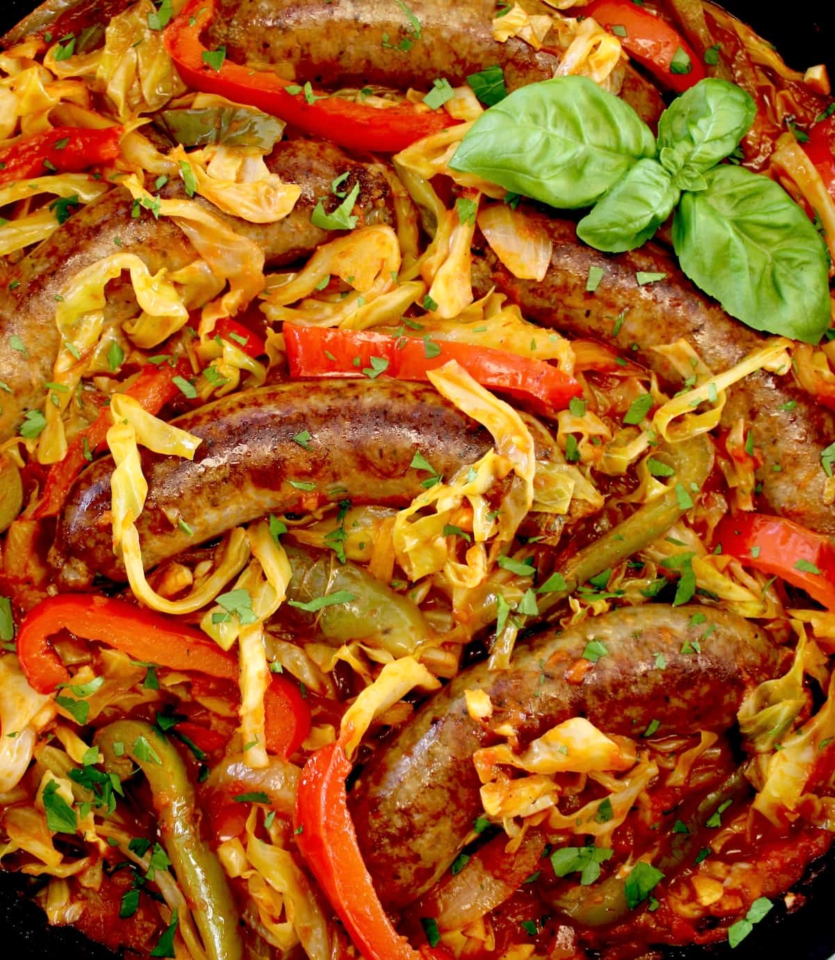 closeup of Italian Sausage and Peppers Cabbage Skillet in skillet with fresh basil garnish