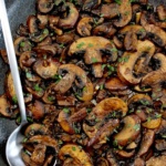 Sautéed Mushrooms in skillet with silver serving spoon on side