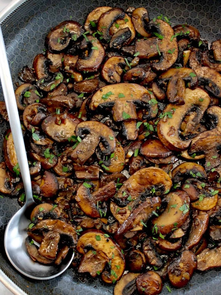 Sautéed Mushrooms in skillet with silver serving spoon on side