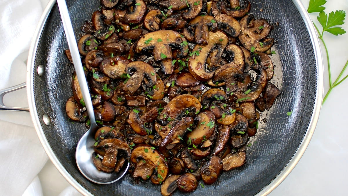 Sautéed Mushrooms in skillet with silver serving spoon
