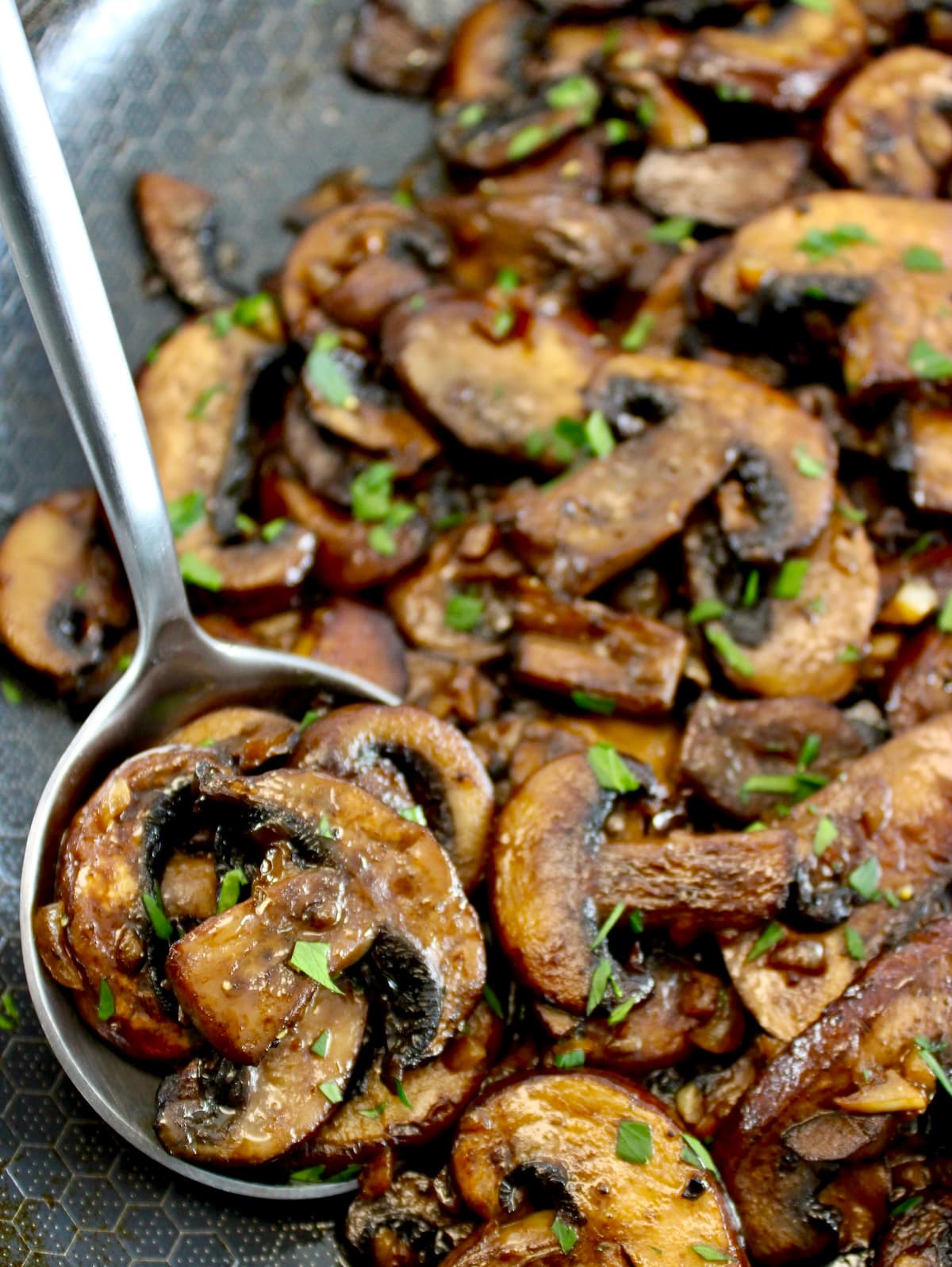 closeup of Sautéed Mushrooms in skillet with silver serving spoon