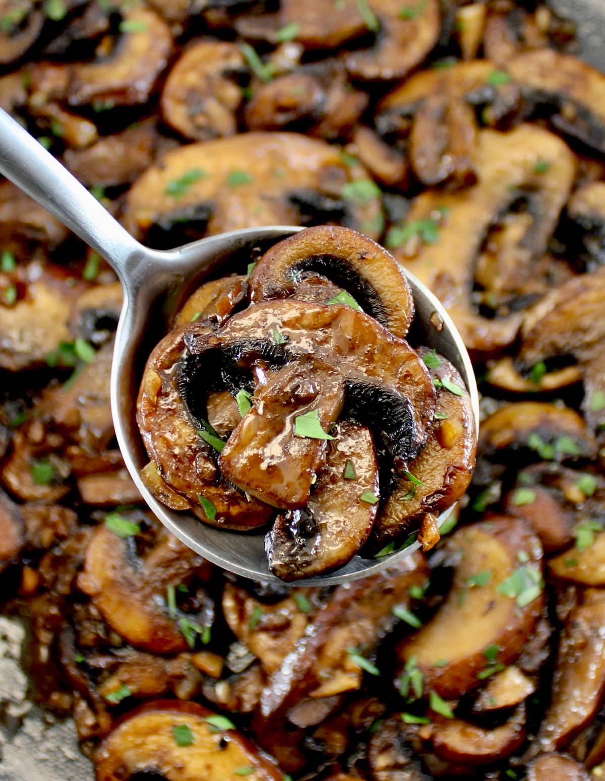 spoonful of Sautéed Mushrooms held up over skillet