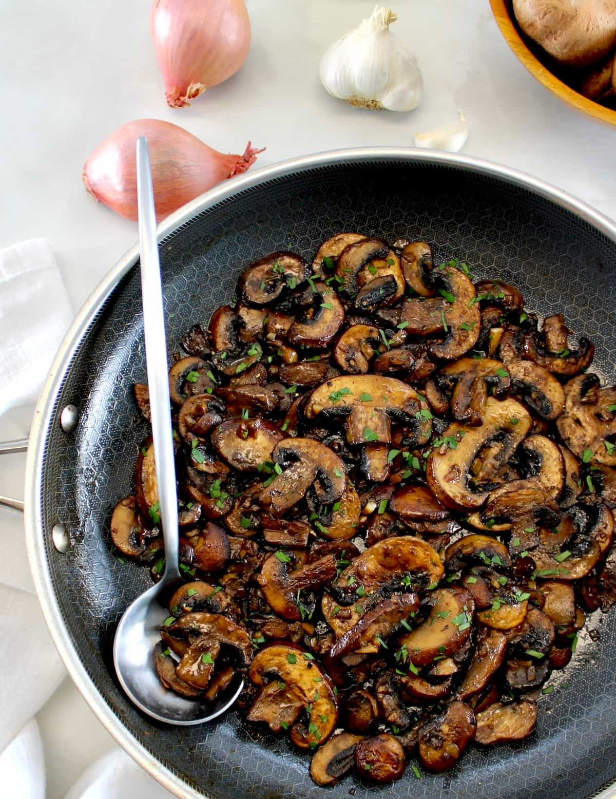 overhead view of Sautéed Mushrooms in skillet with silver serving spoon on side