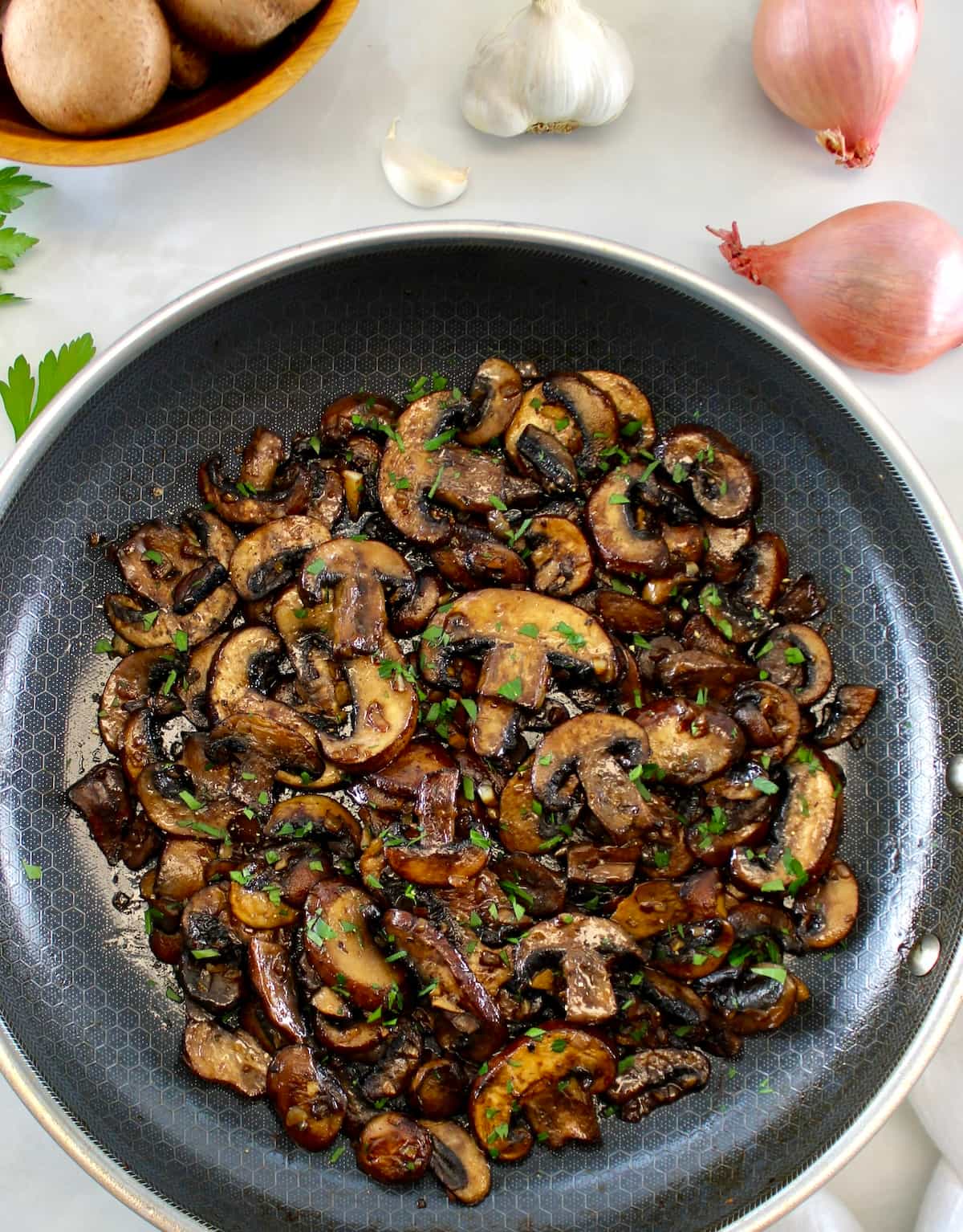 overhead view of Sautéed Mushrooms in skillet with shallot and mushrooms in back