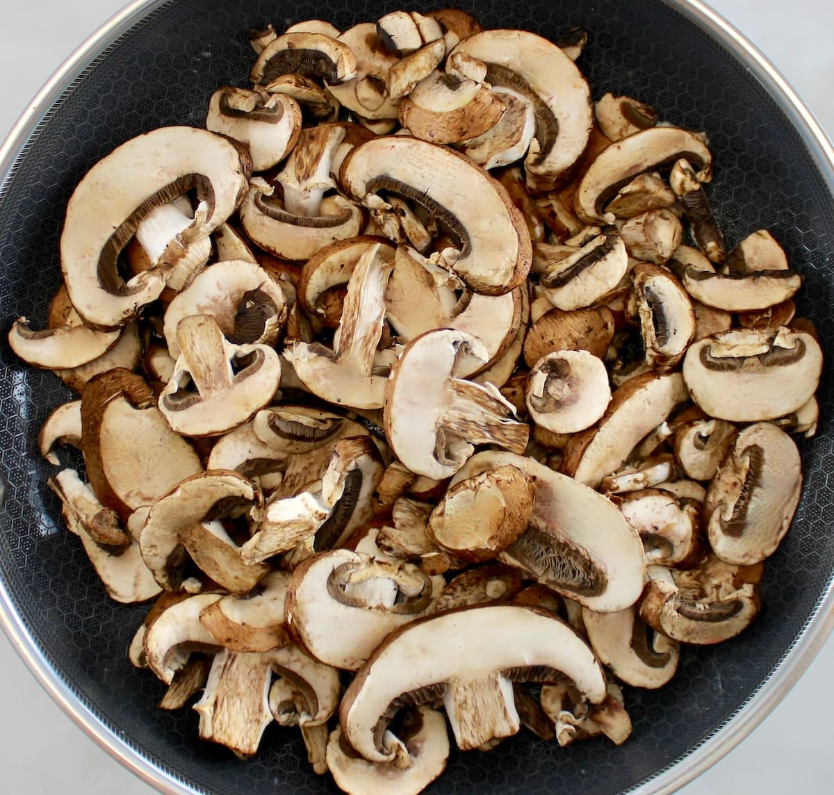 sliced raw baby bella mushrooms in skillet