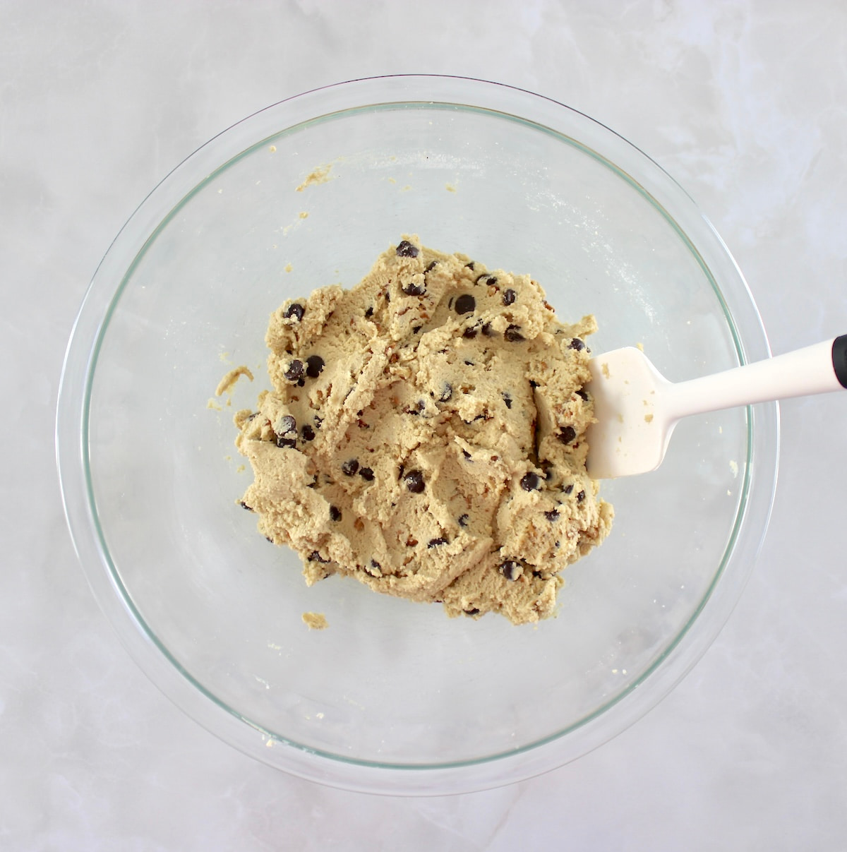 Chocolate Chip Walnut Cookies dough in glass bowl with white spatula