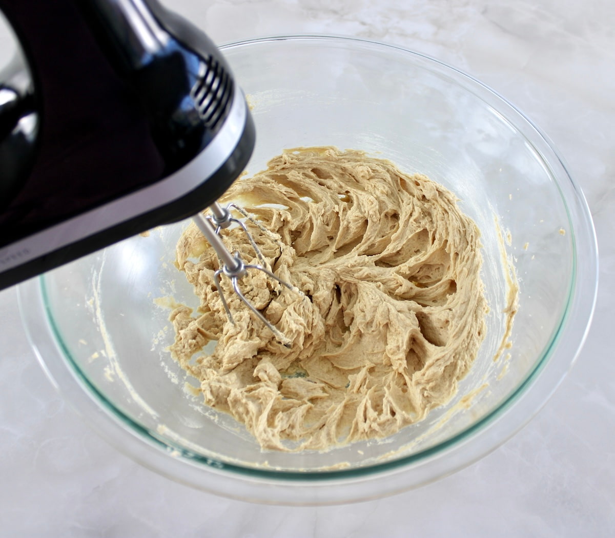Chocolate Chip Walnut Cookies dough being mixed in glass bowl with hand mixer