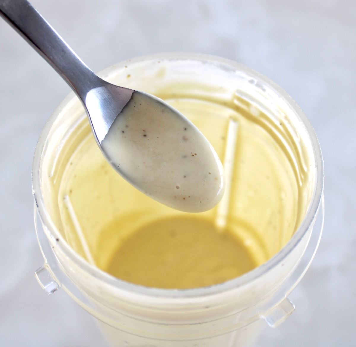 Lemon Tahini Dressing being spooned out of bullet blender cup