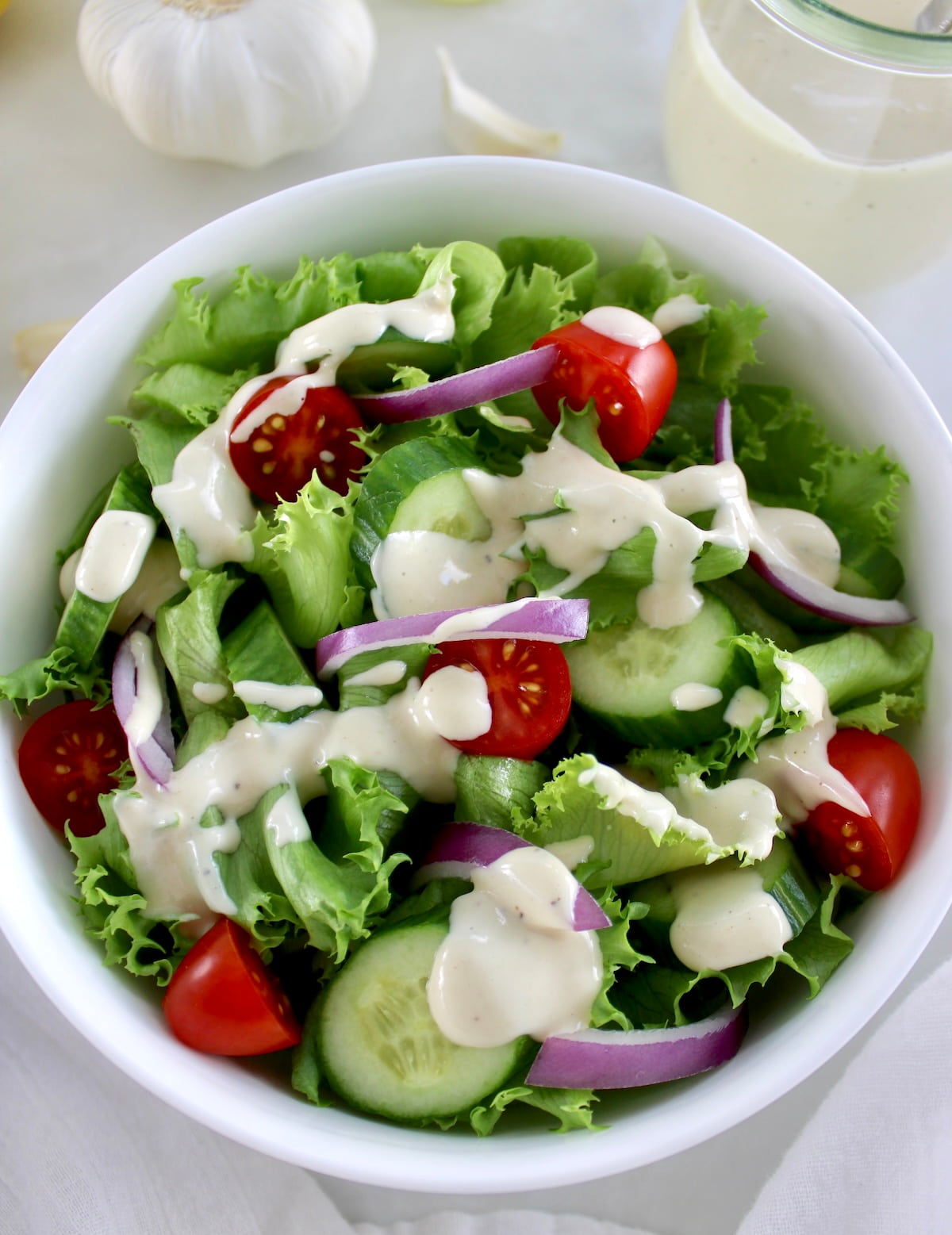 Lemon Tahini Dressing over salad in white bowl