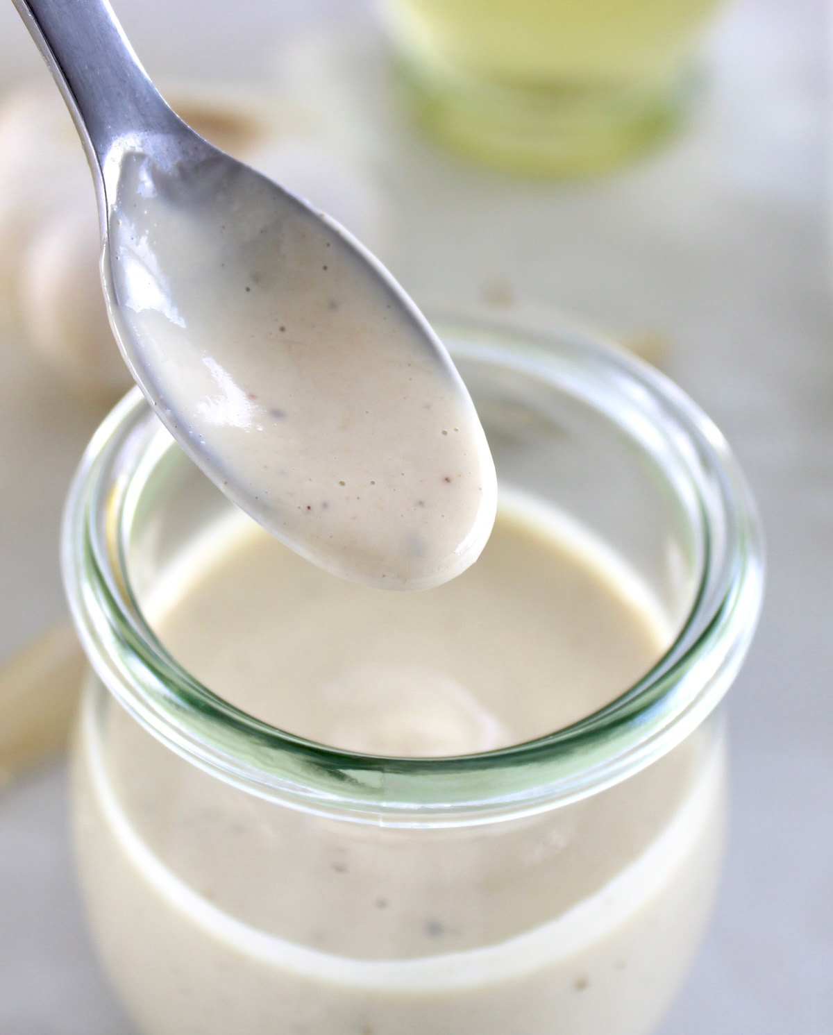 Lemon Tahini Dressing being spooned out of open glass jar