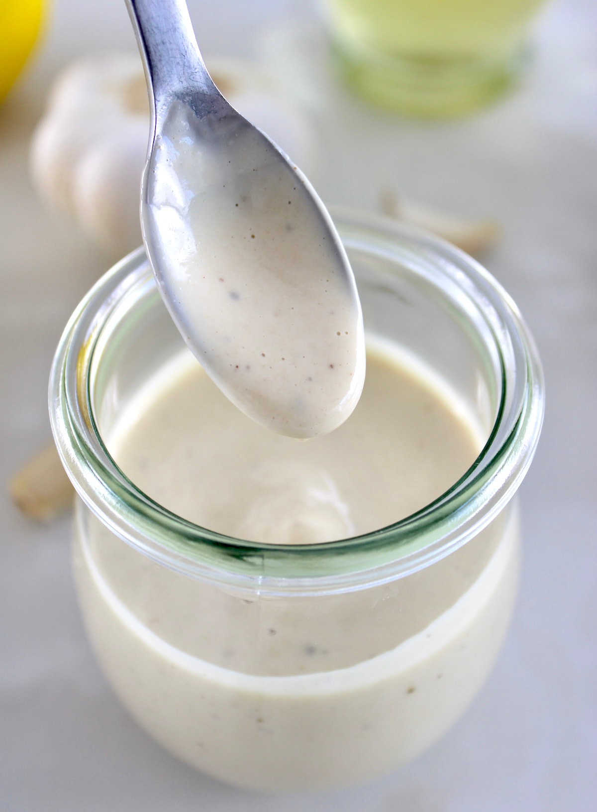 Lemon Tahini Dressing being spooned out of open glass jar