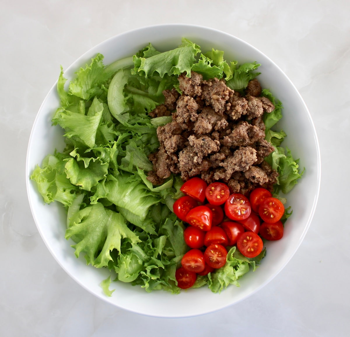 white bowl with lettuce, ground beef and cherry tomatoes
