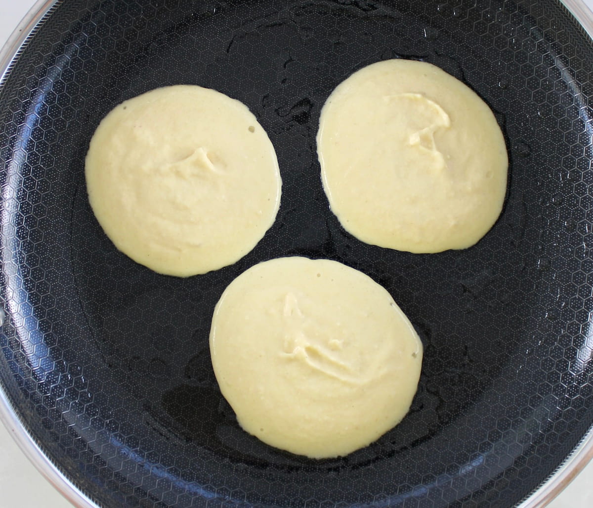 3 pancakes cooking in skillet
