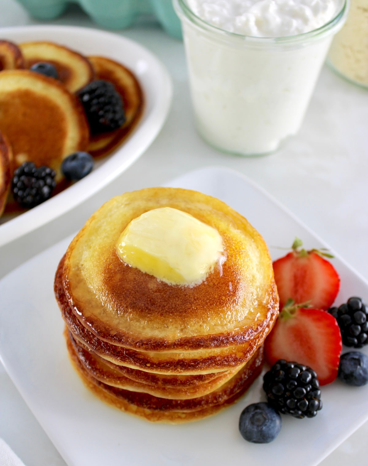 overhead view of Cottage Cheese Pancakes stack with pad of butter on top and berries on side