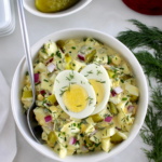 Dill Pickle Egg Salad in white bowl with sliced hard boiled egg on top