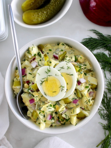 Dill Pickle Egg Salad in white bowl with sliced hard boiled egg on top