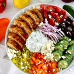 overhead view of Greek Chicken Bowl with lemon and peppers in back