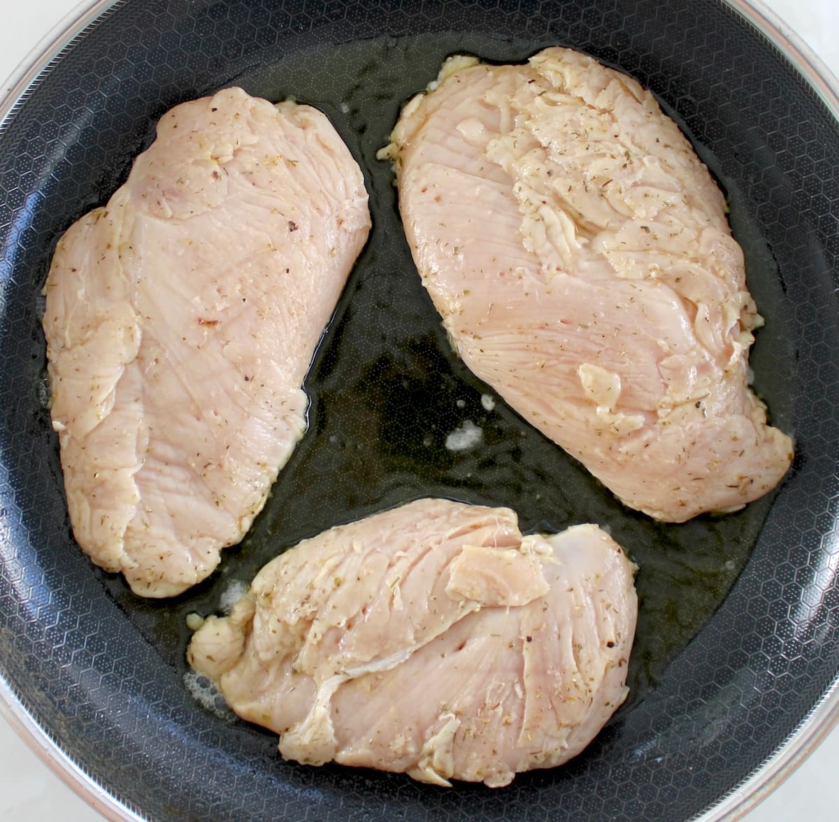 3 marinated chicken breasts cooking in skillet