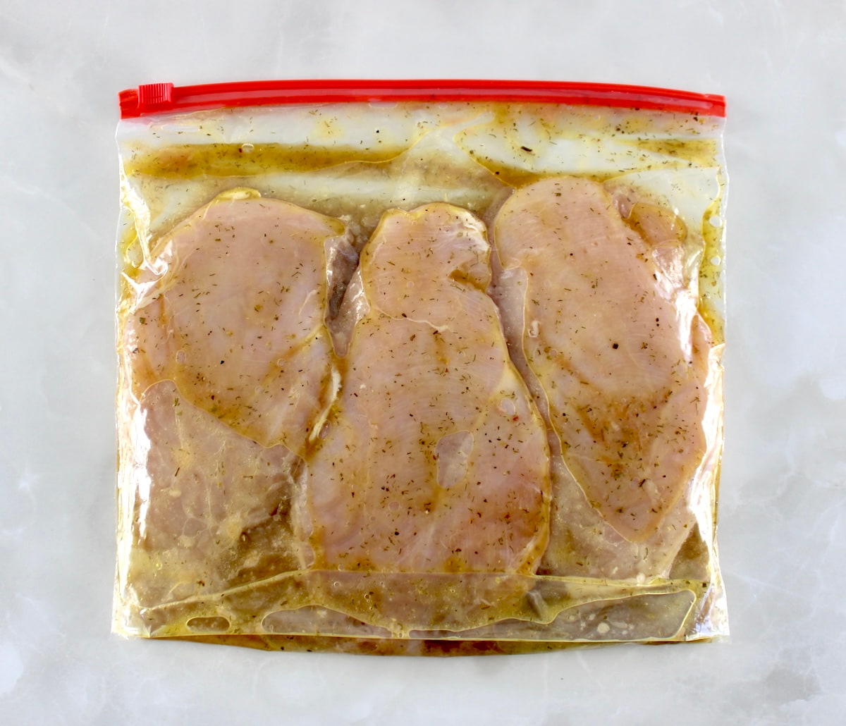 3 chicken breasts marinating in food storage bag