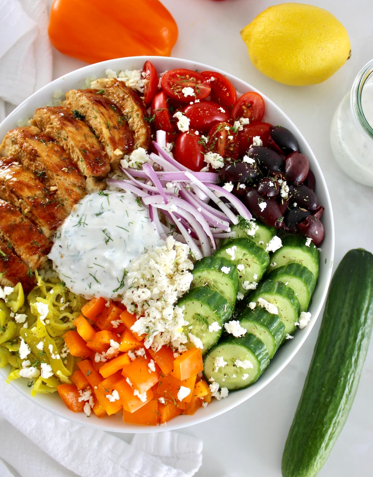 overhead view of Greek Chicken Bowl with fresh veggies in back