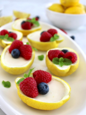 Lemon Posset in lemon halves with fresh berries on top