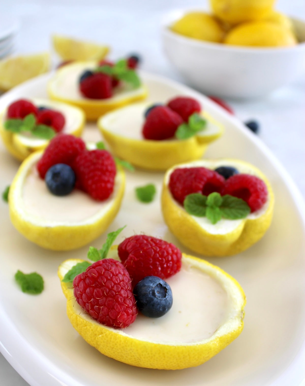 Lemon Posset in lemon halves with fresh berries on top