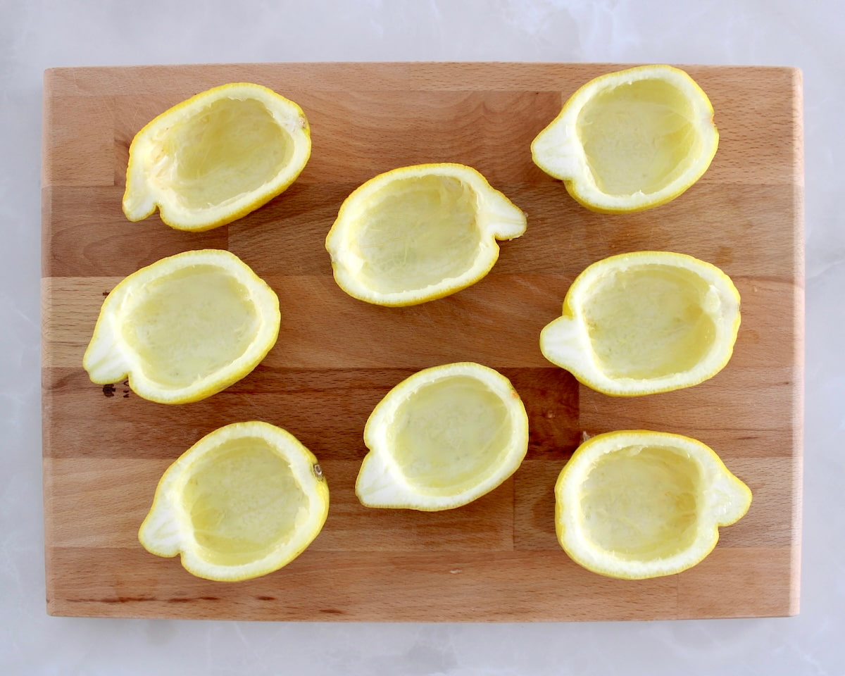 8 lemon halves on cutting board with flesh scooped out