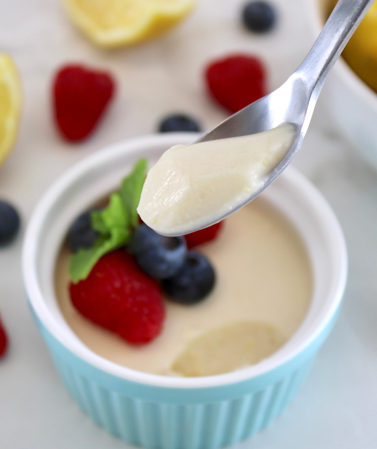 holding up spoonful of Lemon Posset over ramekin