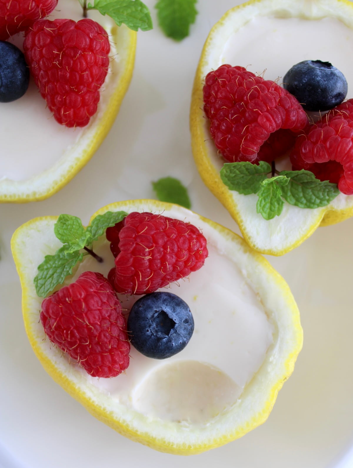 overhead view of Lemon Posset served in lemon halves with fresh berries and bite missing